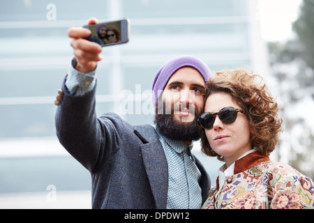 Couple taking a photograph of themselves with a smartphone outdoors Stock Photo