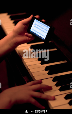 Close up of hands using smartphone whilst playing piano Stock Photo