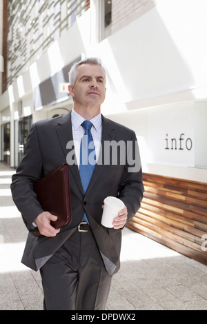 Businessman walking down corridor in office Stock Photo