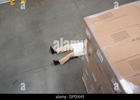 Man lying on floor with cardboard boxes in warehouse Stock Photo