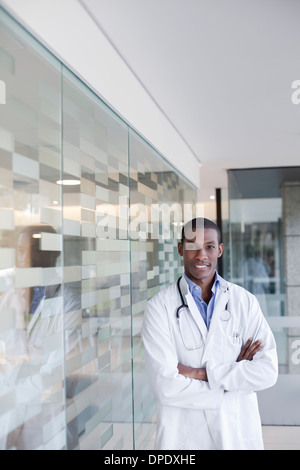 Doctor standing in hospital corridor with arms folded Stock Photo