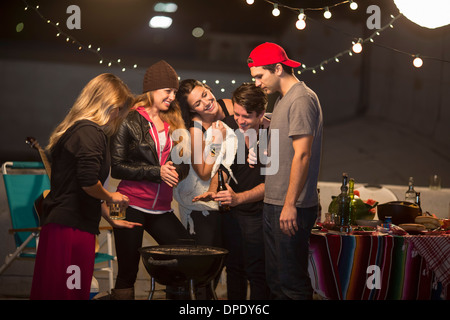 Young adult friends keeping warm at rooftop party Stock Photo