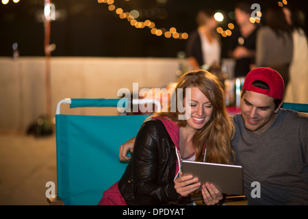 Young couple using digital tablet at rooftop barbecue Stock Photo