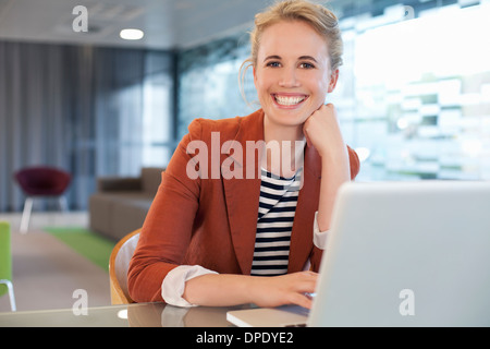 Businesswoman sitting at desk, using laptop Stock Photo