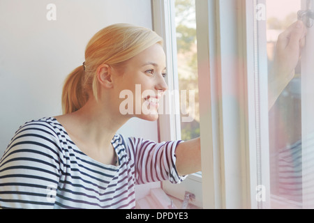 Young woman opening window Stock Photo