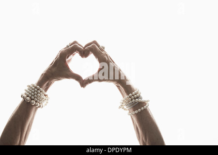 Studio shot of mature woman's hands making heart shape Stock Photo
