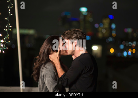 Young couple kissing at rooftop party Stock Photo