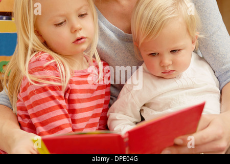 Mother reading picture book with two daughters Stock Photo