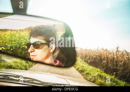 Mirror reflection of young man leaning driving on country road Stock Photo