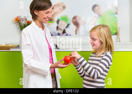 Dentist giving girl apple in dental reception Stock Photo