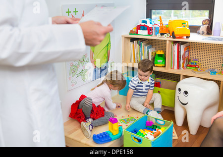 Children playing on floor, dentist in foreground Stock Photo