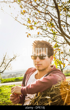 Portrait of young man leaning against haystack Stock Photo
