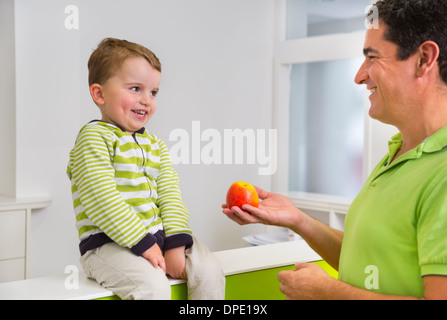 Man giving young boy apple Stock Photo