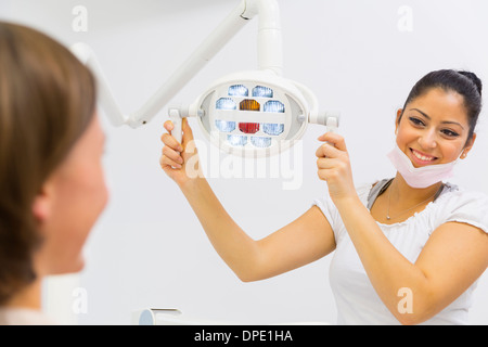 Dental nurse adjusting lights in dentists Stock Photo