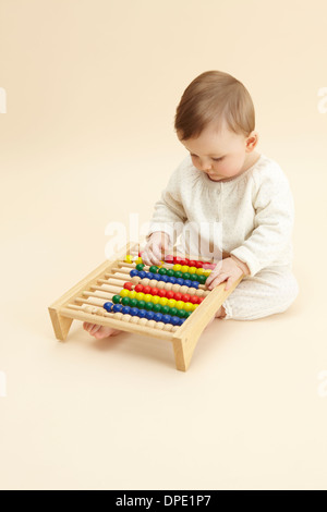 Studio portrait of baby girl playing with abacus Stock Photo