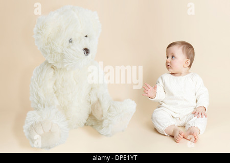 Studio portrait of baby girl next to giant teddy bear Stock Photo