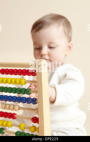 Close up studio portrait of baby girl playing with abacus Stock Photo