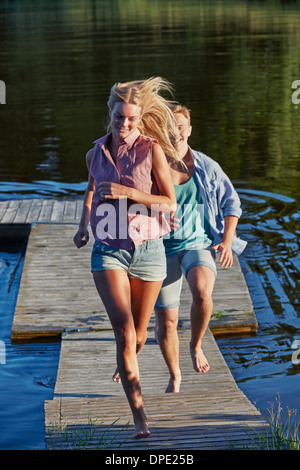 Young adult couple running on pier, Gavle, Sweden Stock Photo