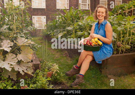 Young woman with harvested vegetables on council estate allotment