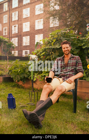 Mid adult man taking a break on council estate allotment Stock Photo