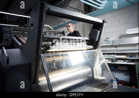 Worker operating printing machine in print workshop Stock Photo