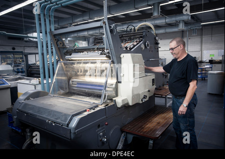 Worker operating print machine in printing workshop Stock Photo