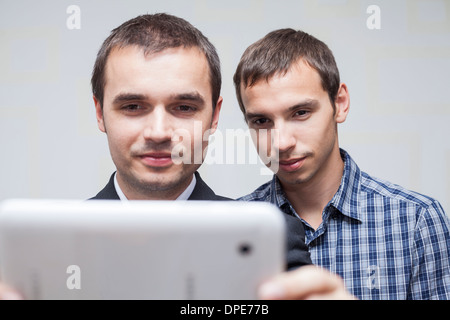 Closeup of two smiling businessmen looking at digital tablet. Stock Photo