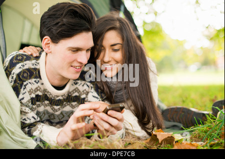 Young couple in tent using smartphone Stock Photo