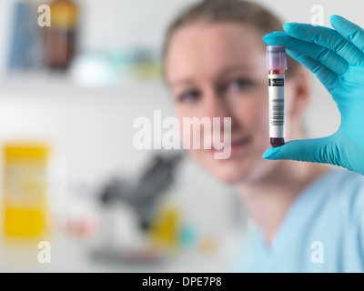Technician holding bar coded blood sample in clinical laboratory Stock Photo