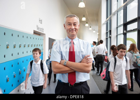 Portrait of male teacher with arms folded in school corridor