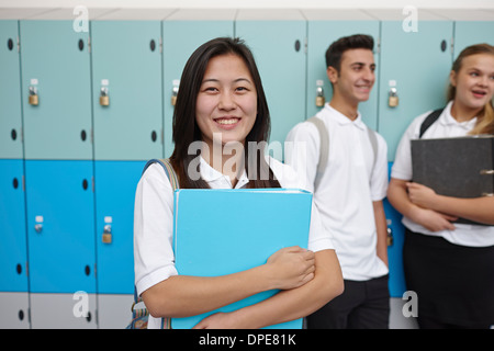 Portrait of teenage schoolgirl next to lockers