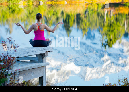 Woman meditating by lake, Bellingham, Washington, USA Stock Photo