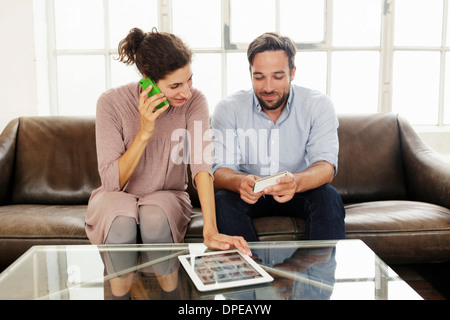 Mid adult couple with digital tablet, woman on cell phone Stock Photo