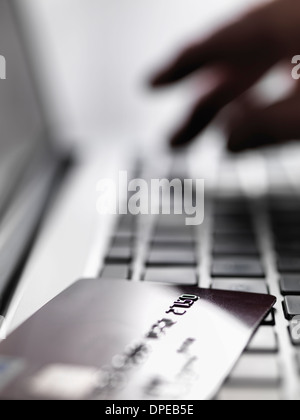 Hand tapping account details on laptop to illustrate internet shopping and internet fraud Stock Photo