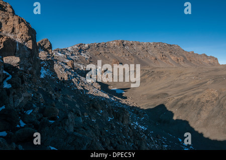 A group of trekkers walking round the crater rim returning to Gilmans Point after visiting Uhuru Peak the summit of Kilimanjaro Stock Photo