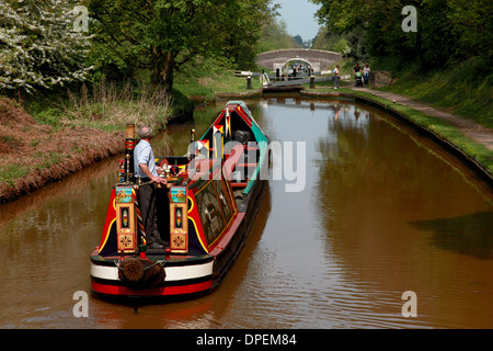 A traditional working narrowboat approaching Lock 6 of the Audlem flight of locks on the Shropshire Union Canal Stock Photo