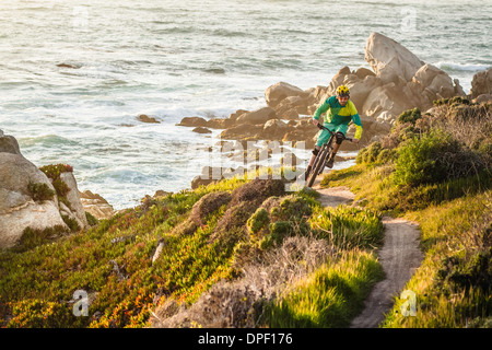 Mountain biker riding up coastal path, Monterey Bay area, California, USA Stock Photo