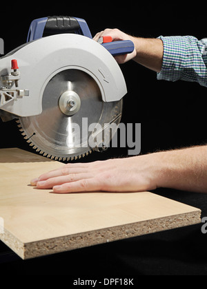 Carpenter cutting flaxboard using sliding compound mitre saw Stock Photo