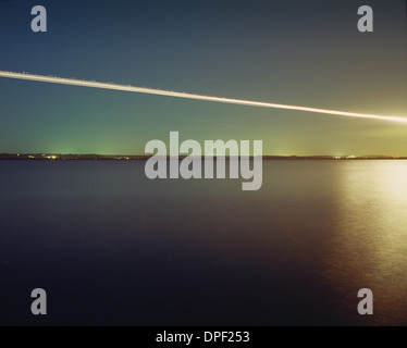 Light trail over water from airborne transport Stock Photo