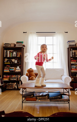 Young girl dancing on top of coffee table Stock Photo