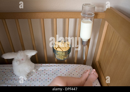 Helpful Ideas for Busy Dads: a feeding machine in cot Stock Photo