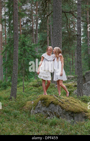 Teenage girls standing on rocks in forest Stock Photo
