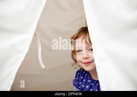 Portrait of female toddler peeking out of tent Stock Photo