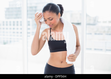 Tired dark haired model in sportswear drying herself with a towel Stock Photo