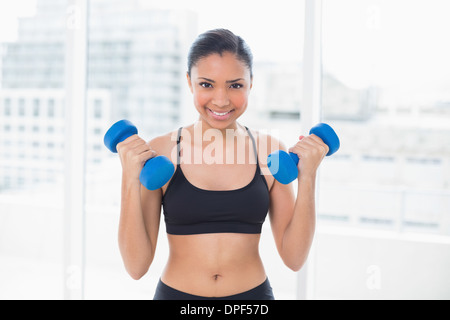 Motivated dark haired model in sportswear exercising with dumbbells Stock Photo