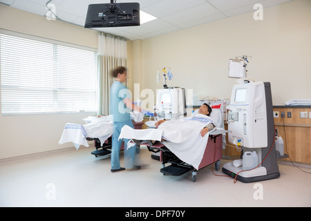 Nurse Walking By Patient Receiving Renal Dialysis Stock Photo