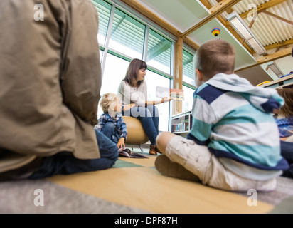 Teacher Reading To Students In Library Stock Photo