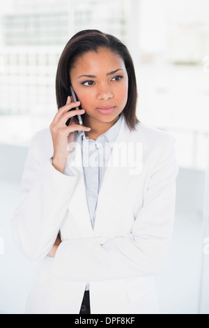 Thoughtful young dark haired businesswoman making a phone call Stock Photo