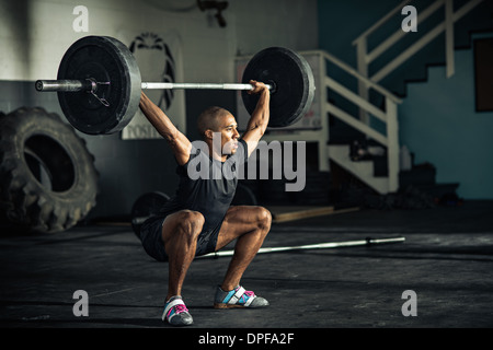 Young man weightlifting barbells in gymnasium Stock Photo