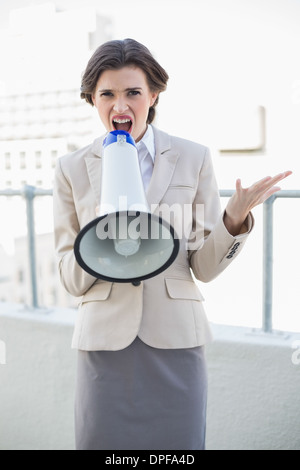 Angry stylish brown haired businesswoman yelling in a megaphone Stock Photo
